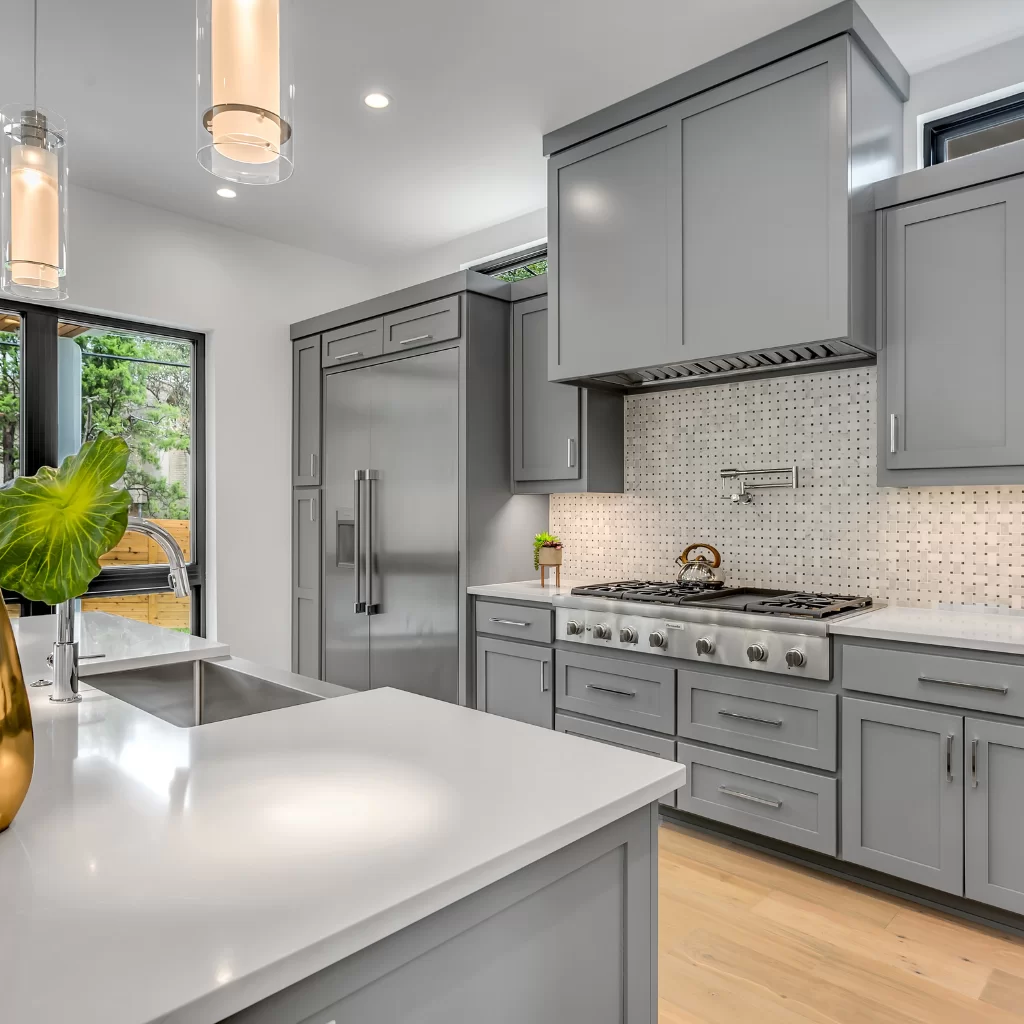 Gray kitchen with central island, pendant lights, and black hardware