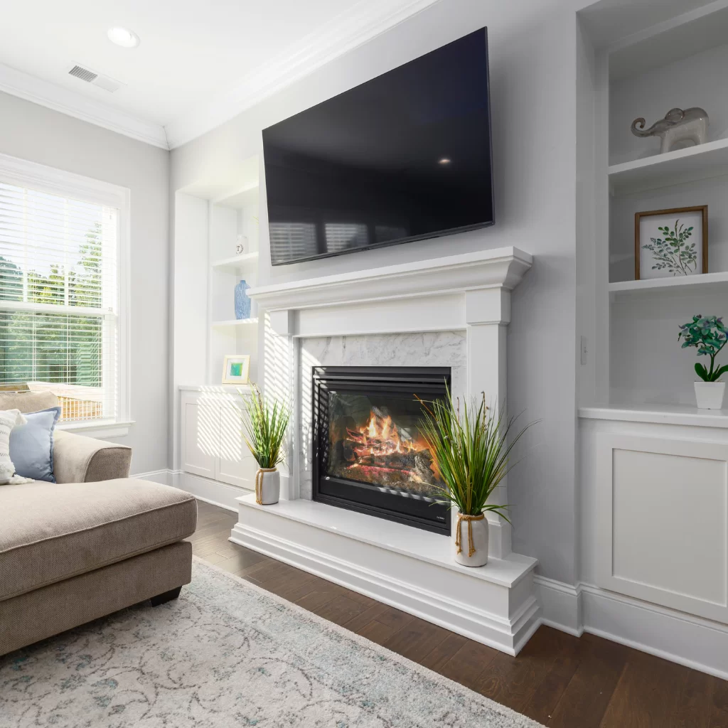 Living room fireplace with mounted TV above and recessed lighting