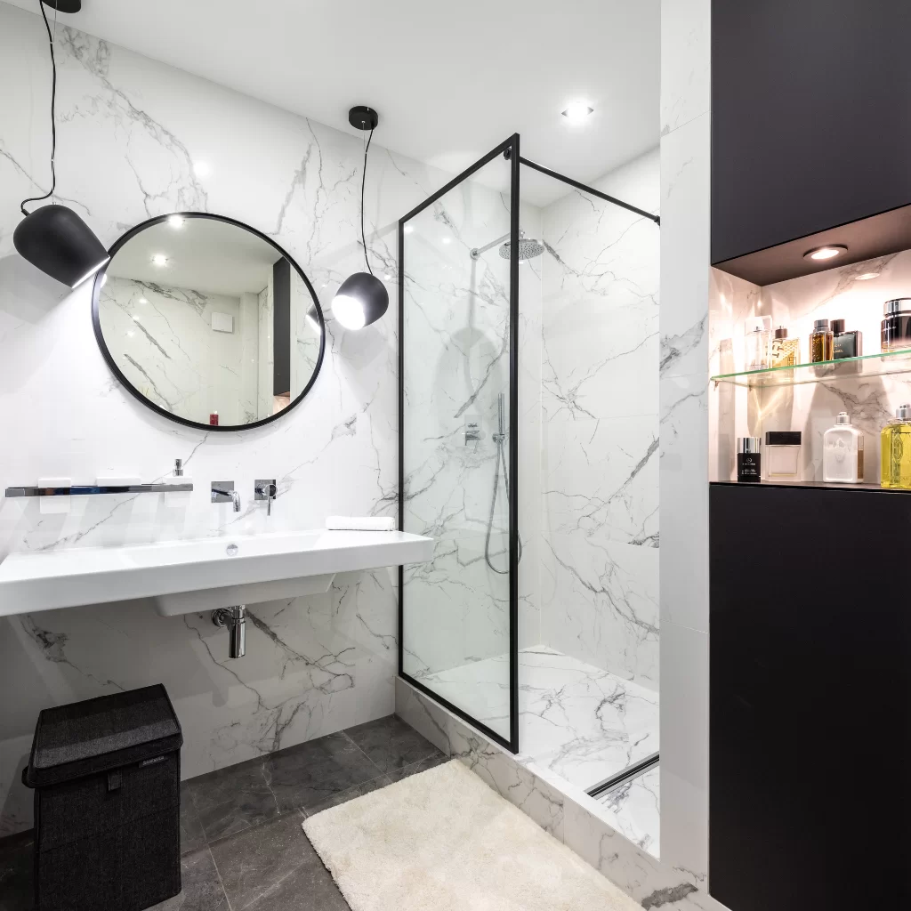 Black-framed glass shower with modern floating vanity and round mirror