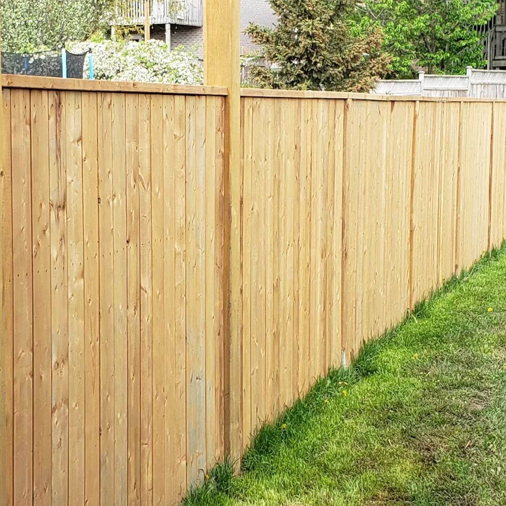 Tall vertical wood privacy fence with clean posts and natural finish