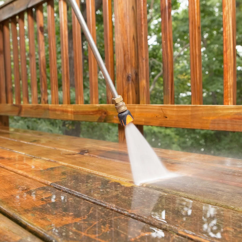 Pressure washing a wooden deck to remove dirt and algae buildup