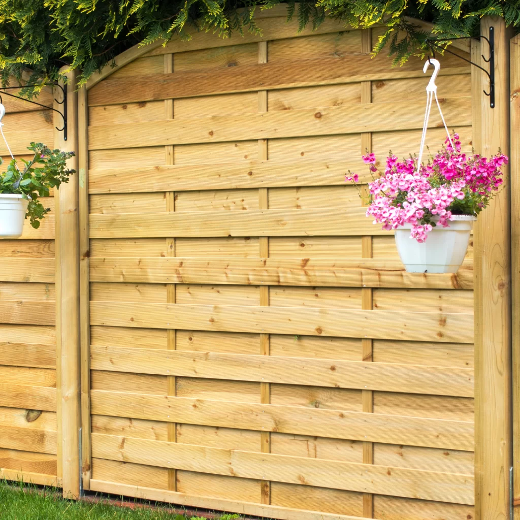 Wooden privacy fence with lattice top and hanging flowers