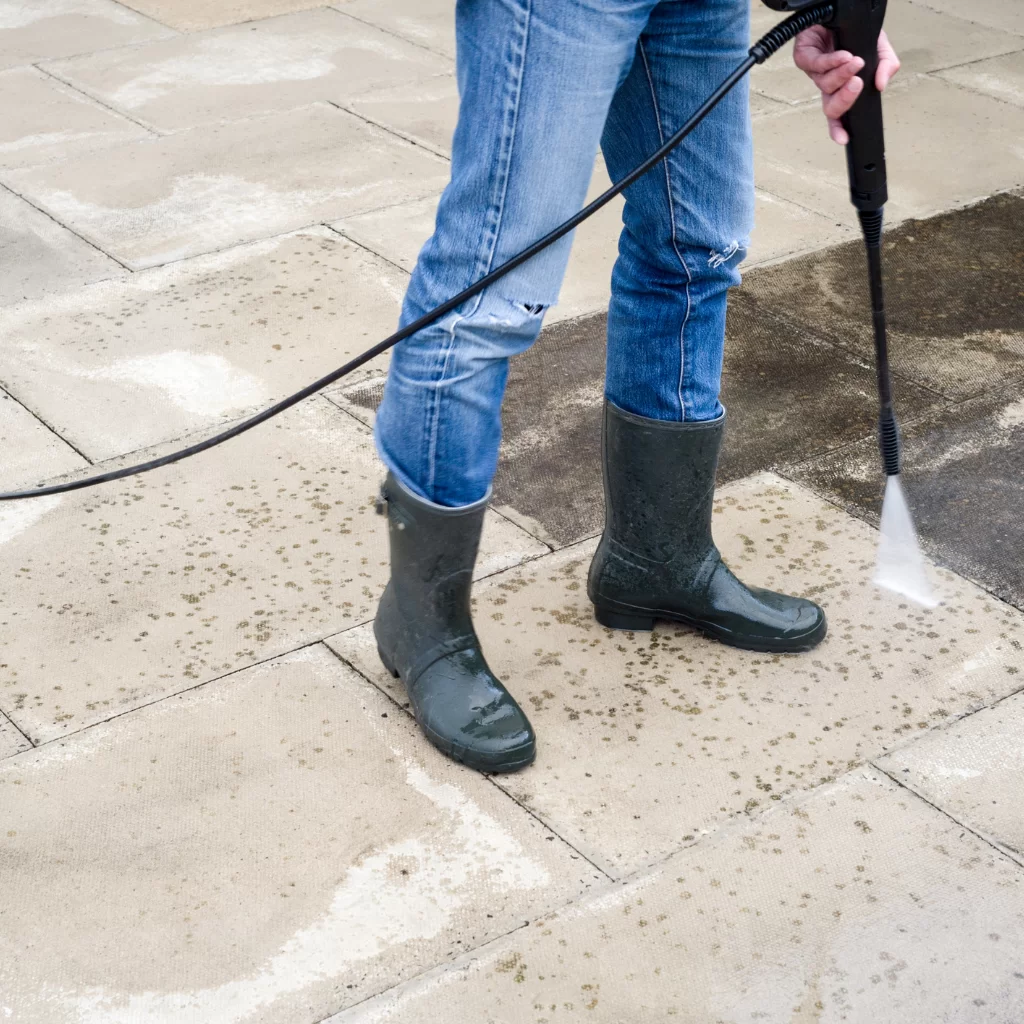 Pressure washing concrete walkway to remove dirt and buildup
