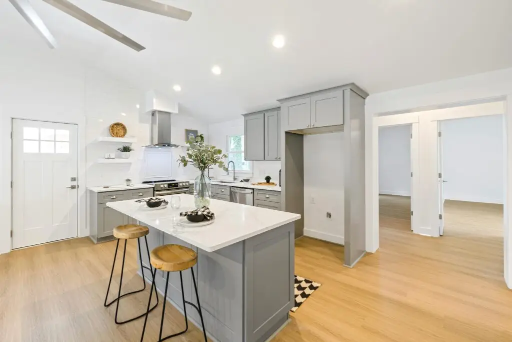 Eco-friendly bamboo flooring in modern kitchen, Bright kitchen interior featuring a marble island and wooden stools with minimalist design.